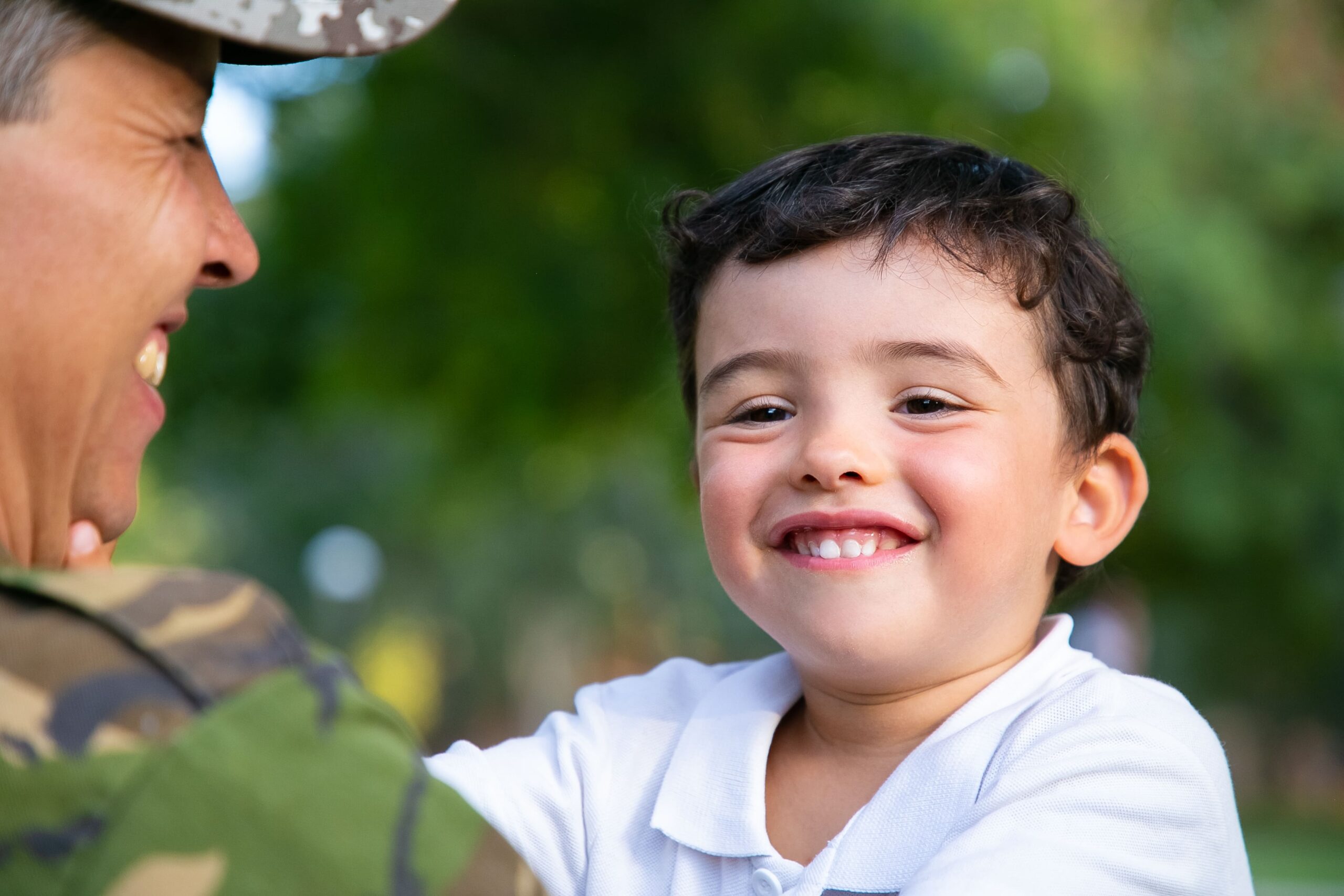 cheerful father holding happy cute little son arms hugging boy outdoors after returning from military mission trip low angle family reunion returning home concept (1)